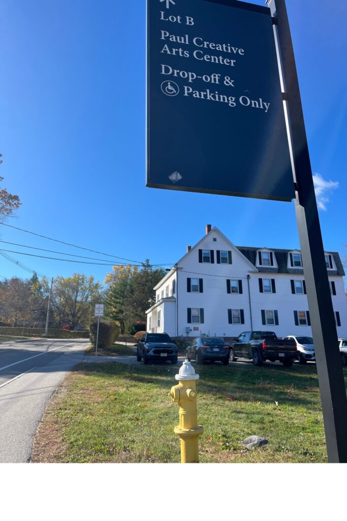 A residential street with parked cars and a parking-only sign under a clear blue sky.